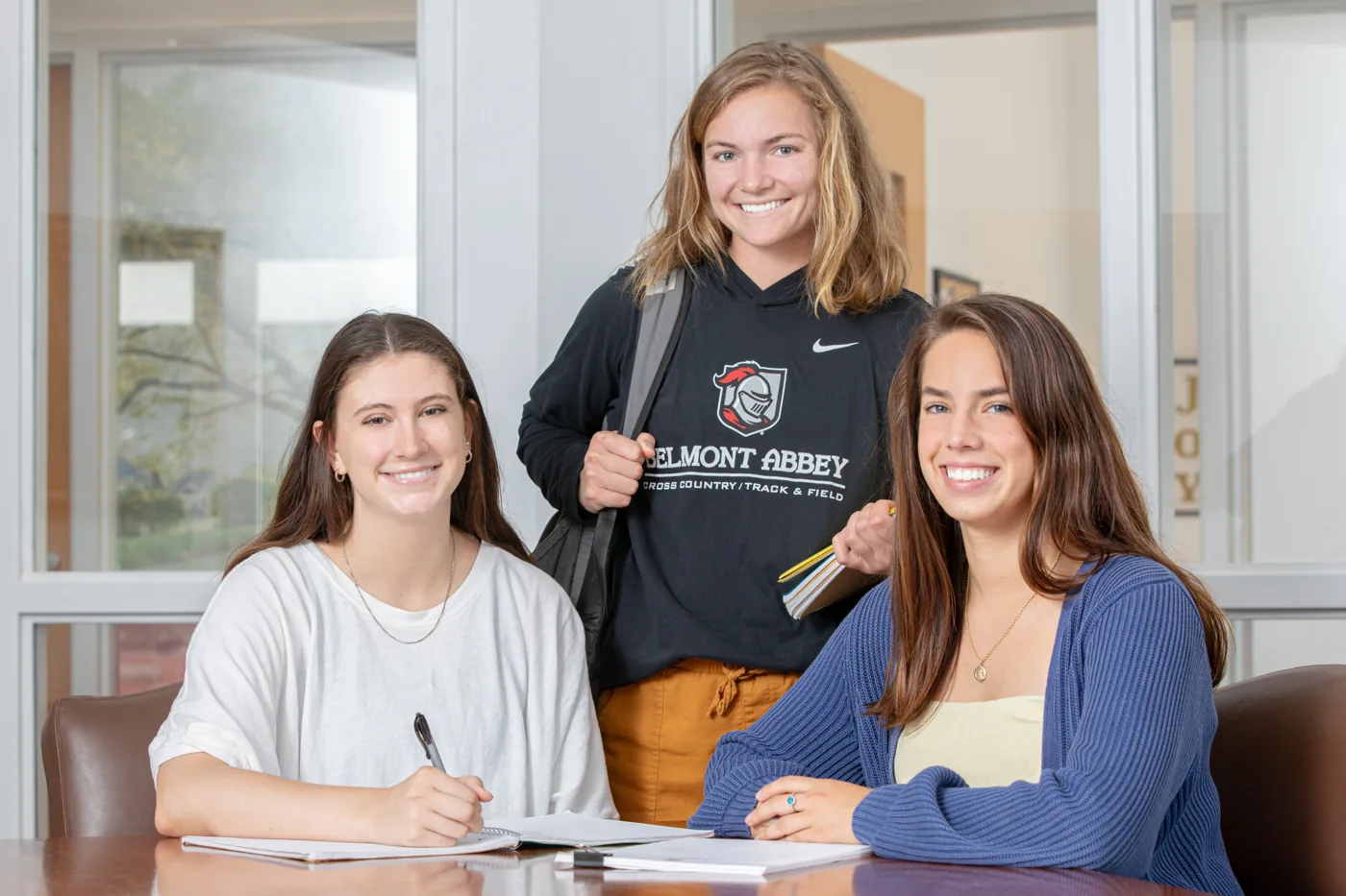 Three Belmont Abbey College students at a table with their notebooks